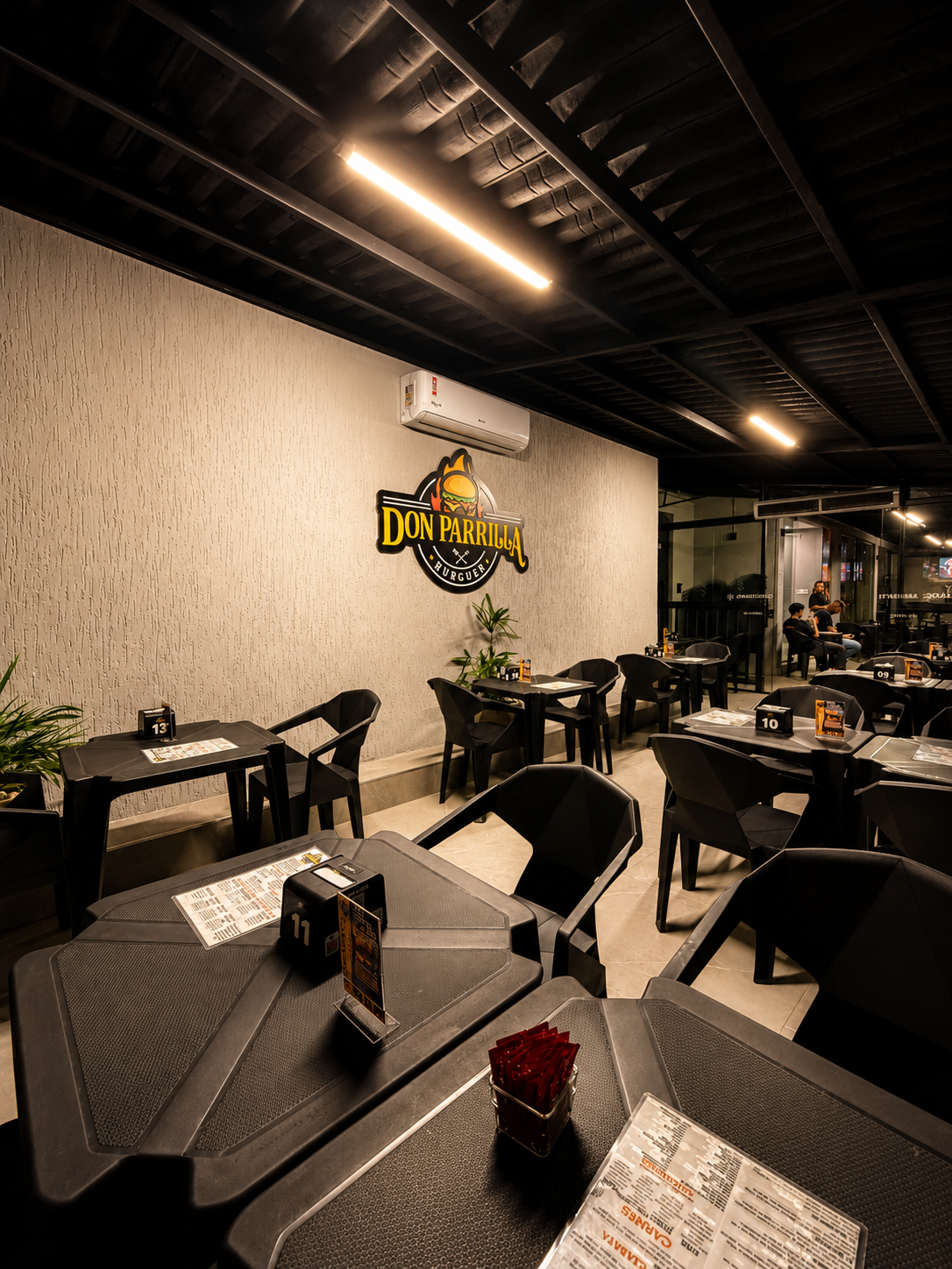 Ambiente interno do Don Parrilla Burguer com letreiro da marca iluminado